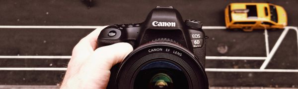 hand holding canon camera in front of streetscape