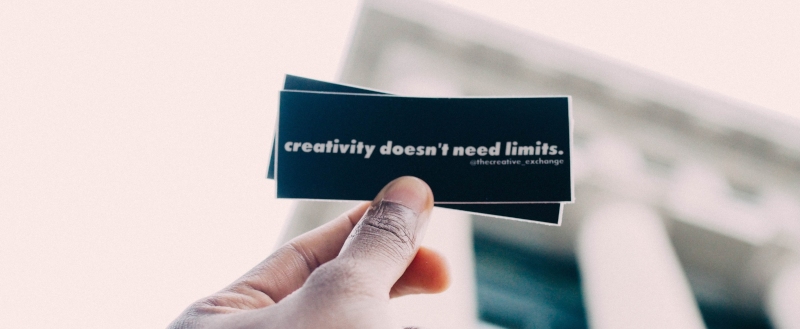 hand holds up small card reading 'creativity doesn't need limits'