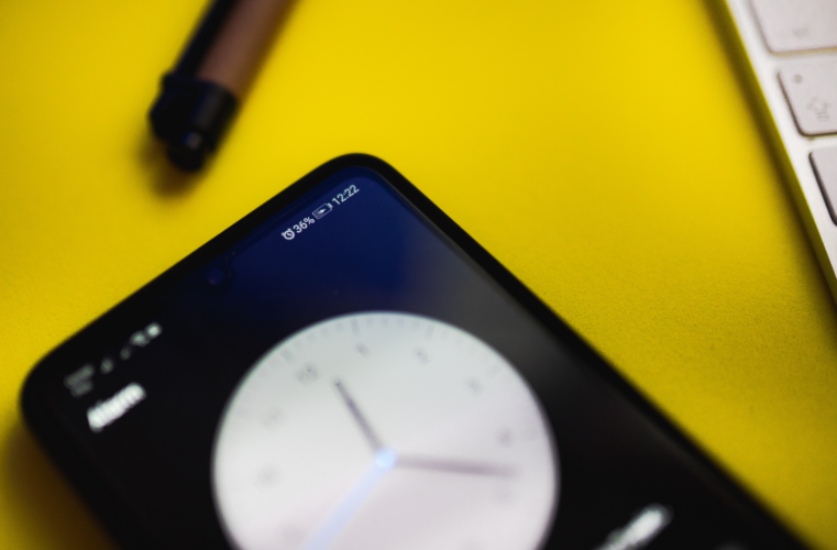 iphone on yellow desk displaying analog clock