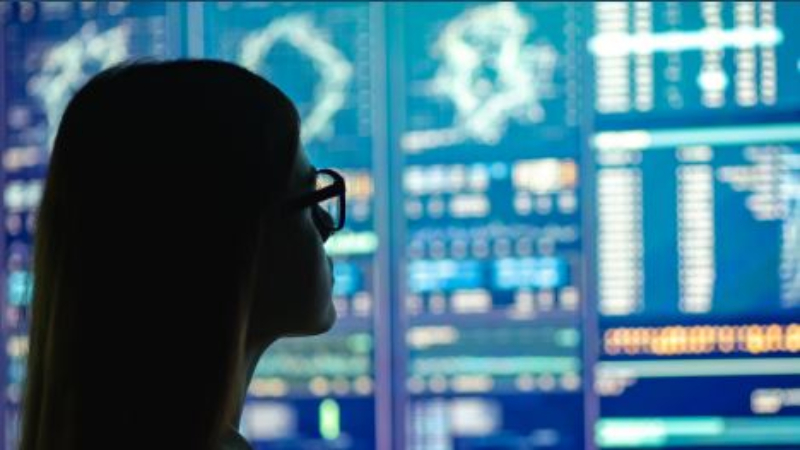 woman in silhouette in front of data display screens