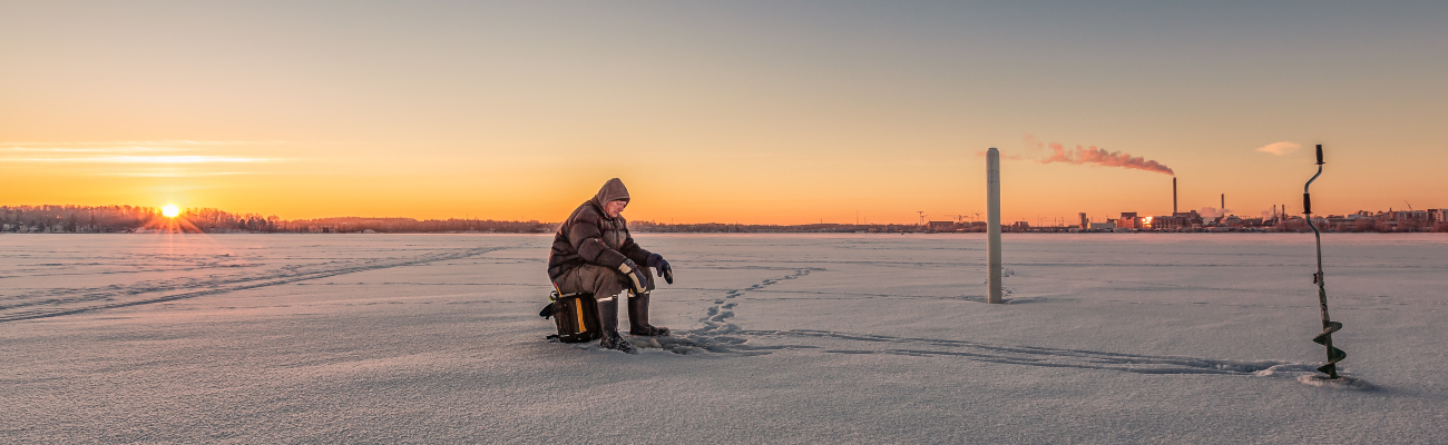 Man in isolation in a snow field at sunset with a factory in the distance